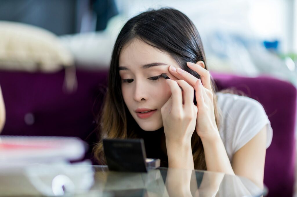 woman is putting make up on yourself eyebrows with the eyebrows pencil or brush.